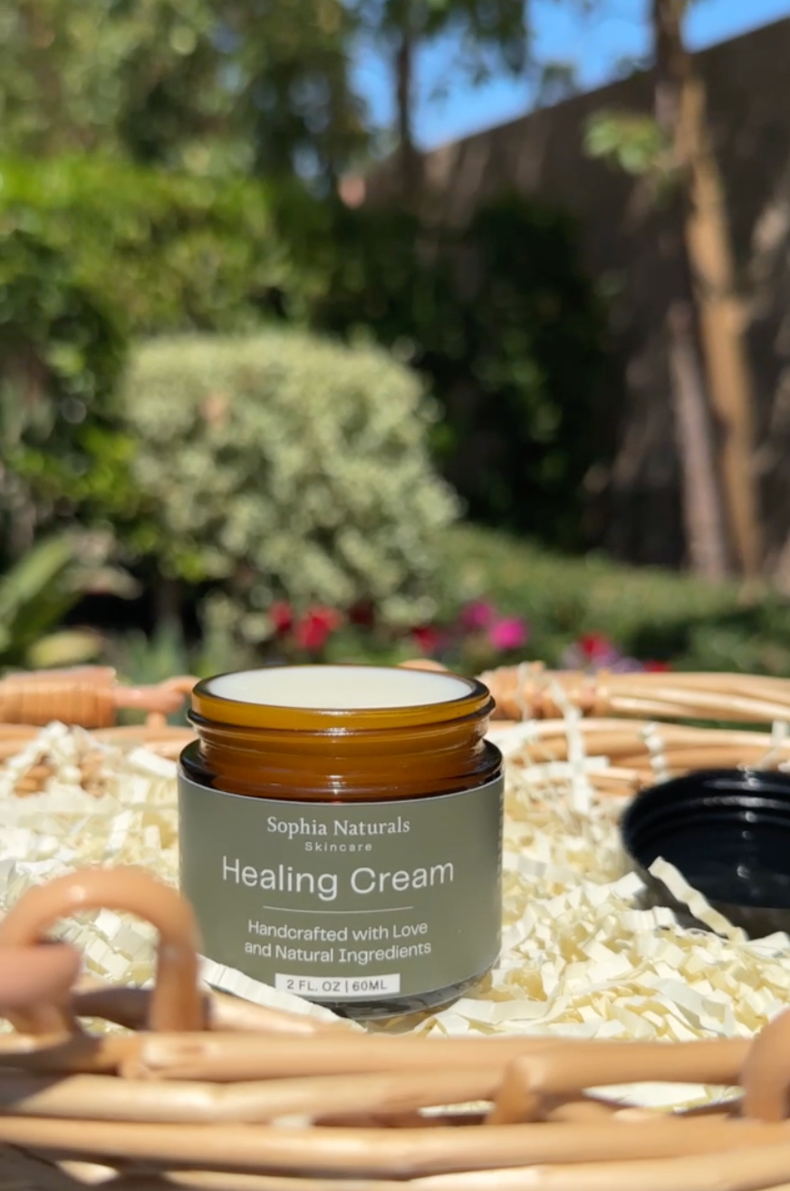 Jar of Sophia Naturals Healing Cream on a woven surface with a garden background